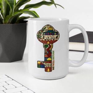 May include: White ceramic mug with a colorful key design. The key is made up of different images, including a building with a dome, a tree, and a winding path. The text "WE WILL RETURN" is written vertically on the right side of the key.