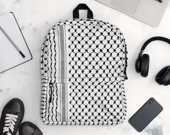 May include: A white backpack with a black and white geometric pattern, a black handle, and a front zipper. The backpack is surrounded by a pair of black sneakers, a notebook, a pen, a laptop, headphones, and a smartphone.