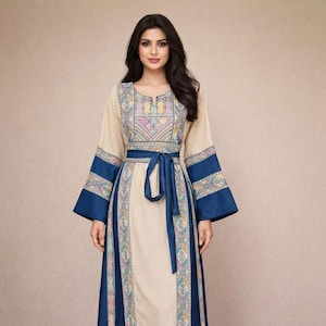 May include: A long, beige dress with intricate embroidery around the neckline and sleeves. The dress features a navy blue belt and accents, with a flowing skirt. The sleeves are long and flared, and the dress has a modest neckline. The dress is suitable for special occasions.