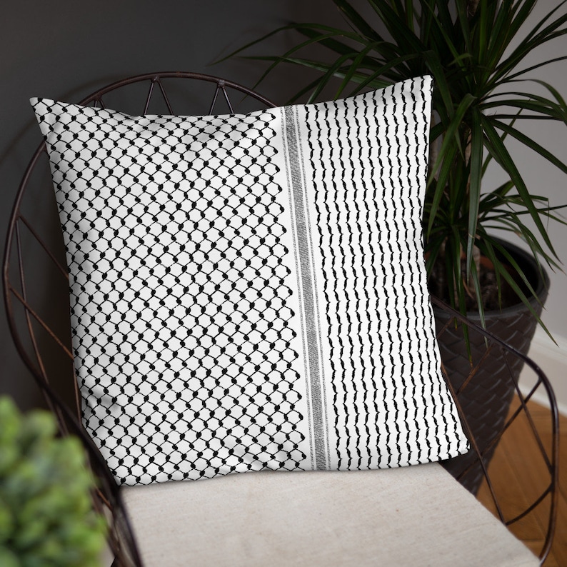 May include: Black and white patterned throw pillow with a geometric design. The pillow is on a chair with a black metal frame.