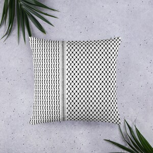 May include: A white pillow with a black and white geometric pattern. The pattern is a traditional Palestinian keffiyeh design.