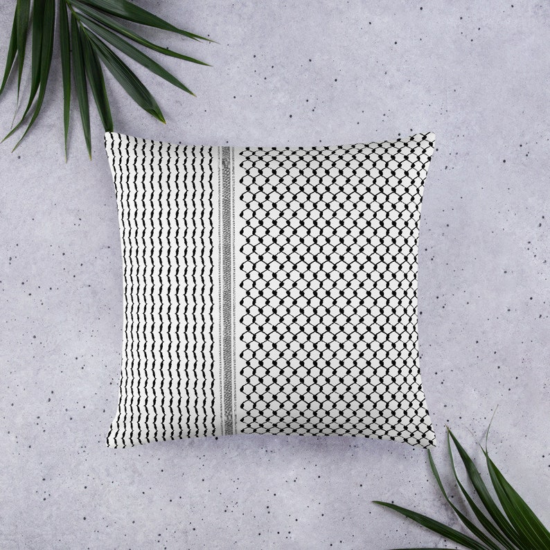 May include: A white pillow with a black and white geometric pattern. The pattern is a traditional Palestinian keffiyeh design.