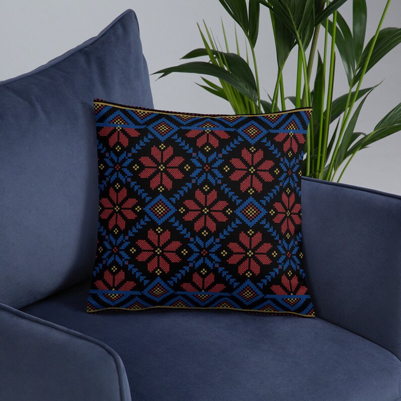Pu&ograve; includere: Un cuscino nero con un motivo geometrico rosso, blu e giallo. Il cuscino &egrave; seduto su un divano blu.