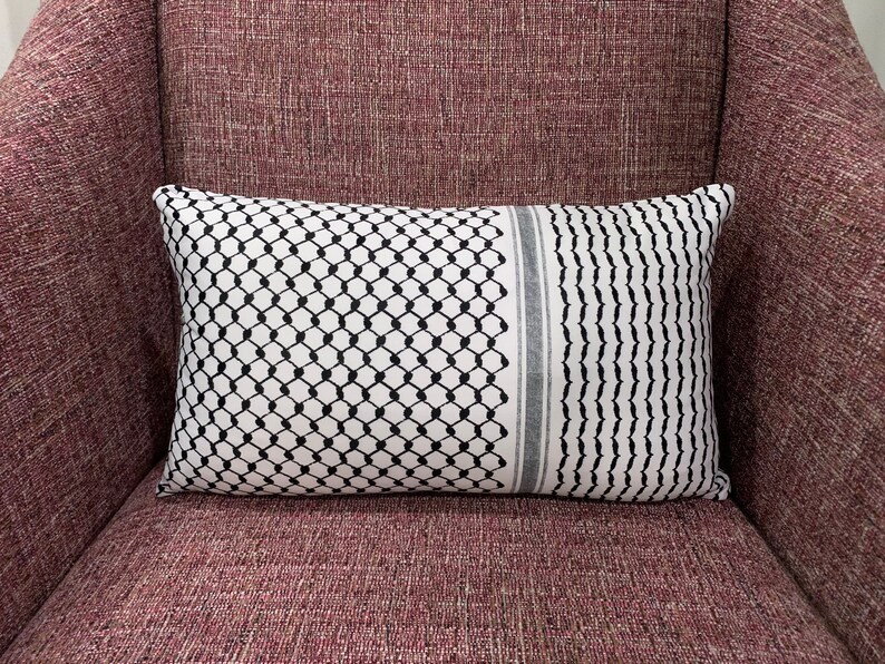 May include: A black and white patterned throw pillow with a gray stripe down the center, resting on a burgundy armchair.