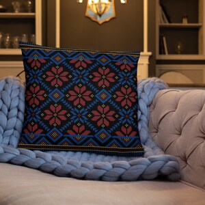Pu&ograve; includere: Un cuscino decorativo con sfondo nero e un motivo geometrico colorato in tonalit&agrave; di rosso, blu e giallo. Il motivo presenta fiori e diamanti stilizzati.