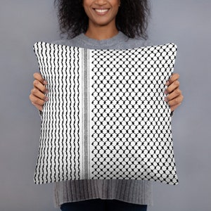 May include: A black and white patterned throw pillow with a geometric design. The pillow is being held by a person.