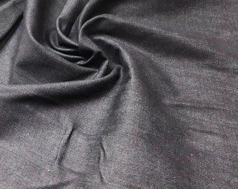 May include: Close-up of dark gray denim fabric with visible texture and folds. The fabric appears to be a medium weight, suitable for various sewing projects. The lighting highlights the subtle variations in the material's surface.