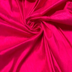May include: A close-up shot of a vibrant, hot pink fabric. The material is gathered and swirled, creating a textured effect with highlights and shadows. The fabric has a slight sheen, suggesting a satin or silk-like texture.