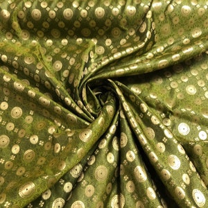 Op de afbeelding: Groene stof met een gouden brokaatpatroon van cirkels en kleine bloemen.
