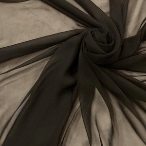 Peut inclure: Gros plan sur un tissu noir transparent, disposé en spirale. Le tissu est léger et translucide, avec un drapé fluide et élégant. La couleur sombre et la texture suggèrent un intérêt pour les textiles et la mode.