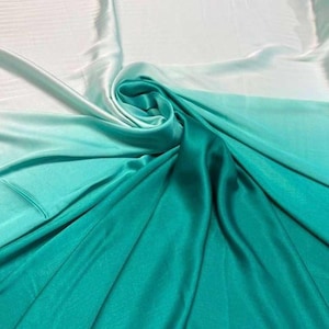 May include: A folded piece of fabric with a gradient of colors. The fabric transitions from white to light teal, then to a deeper teal, and finally to a rich, dark teal. The fabric has a silky, smooth texture and a slight sheen.