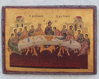 Può includere: Un'icona in legno che rappresenta l'Ultima Cena, con Gesù e i suoi discepoli seduti attorno a un tavolo. L'icona è dipinta in uno stile tradizionale con accenti dorati e il testo "Ο ΔΕΙΠΝΟΣ  DE  Ο ΜΥΣΤΙΚΟΣ" in alto.