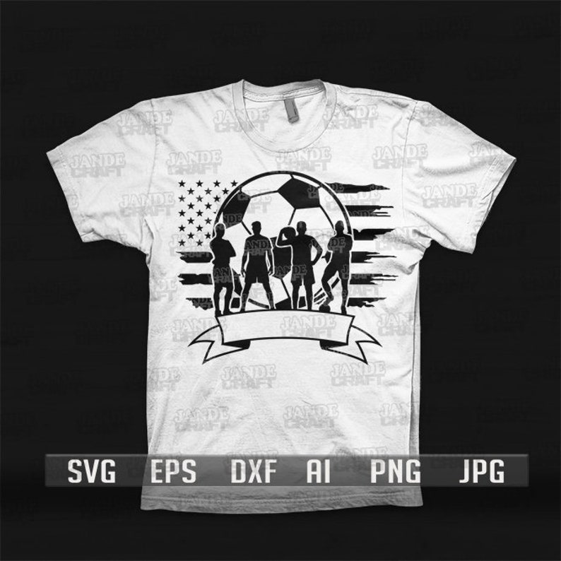 K&ouml;nnte beinhalten: Wei&szlig;es T-Shirt mit einem Fu&szlig;ball-Design, das die amerikanische Flagge und vier Spielersilhouetten enth&auml;lt. Am unteren Rand befindet sich ein Banner. Das T-Shirt hat kurze &Auml;rmel und einen Rundhalsausschnitt. Das Design ist in Schwarz.