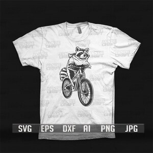 May include: A white t-shirt featuring a black and white illustration of a raccoon riding a bicycle. The raccoon is wearing a hooded sweatshirt. The t-shirt has the text "JADE CRAFT" repeated on it.