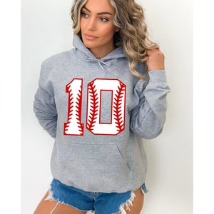 May include: A gray hoodie with a front pocket and a drawstring hood. The number "10" is displayed on the front in a baseball-style design, with a white center and red stitching.