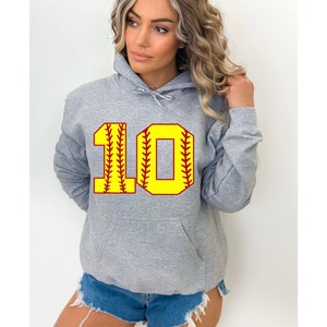 May include: A grey hooded sweatshirt featuring a large yellow and red number 10 on the front, designed to look like a softball. The sweatshirt has a front pocket and a drawstring hood. The number is outlined in red with yellow stitching.