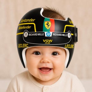 Peut inclure: Un casque orthopédique crânien noir avec le logo Ferrari, du texte jaune incluant Santander, Bitdefender, VGW PLAY et LECLERC, et du texte blanc incluant RICHARD MILLE et HP. Le casque possède une doublure intérieure blanche et une sangle latérale noire.