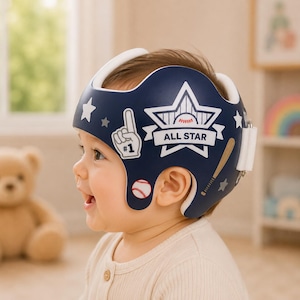 Könnte beinhalten: Ein marineblauer Schädelorthesenhelm mit weißen Grafiken eines Baseballs, eines Schlägers, eines Nummer-eins-Schaumstofffingers und Sternen. Der Text ALL STAR ist in Weiß innerhalb eines großen Sternmotivs an der Seite des Helms aufgedruckt.