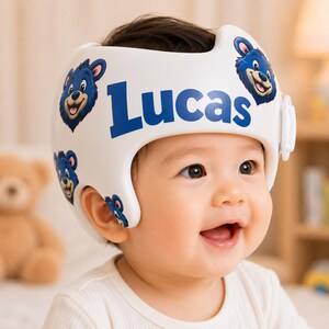 May include: A white cranial orthosis helmet featuring a repeating pattern of blue bear faces and the name Lucas printed in large blue letters across the front. The helmet has a smooth, moulded plastic exterior with cutouts for the ears.