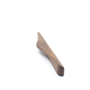 Może przedstawiać: Drewniany uchwyt do szafki w ciemnym kolorze brązu o zakrzywionym kształcie.