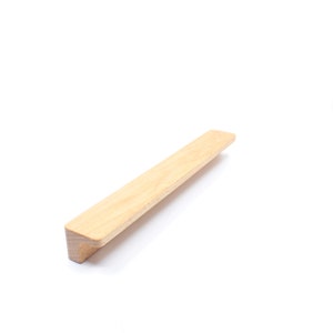 Puede incluir: Un tirador de armario de madera clara con un diseño ligeramente inclinado.