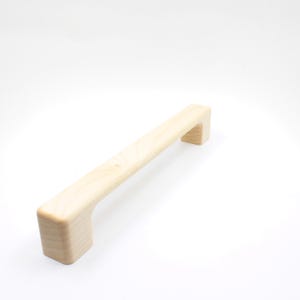 Könnte beinhalten: Ein heller Holz-Schrankgriff mit rechteckiger Form und abgerundeten Kanten.