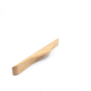 Könnte beinhalten: Ein hellbrauner, gebogener Holzknauf für Schränke.