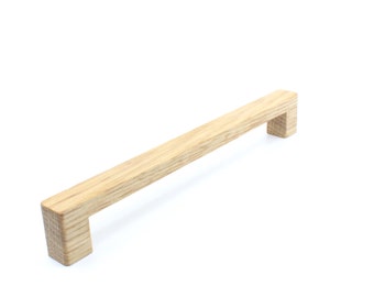 May include: A light brown wooden cabinet pull with a rectangular shape. The pull has a smooth, natural finish.