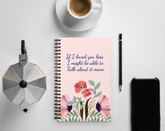 Może przedstawiać: Różowy notes w spirali z kwiatowym wzorem i tekstem "Jeśli kochałbym cię mniej, może mógłbym o tym więcej mówić".