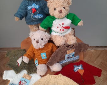 May include: Three plush teddy bears wearing knitted jumpers, one in blue with clouds and a plane, one in green and white with red text, and one in orange. Four additional jumpers are displayed in red, yellow, white, and olive green with various patches.