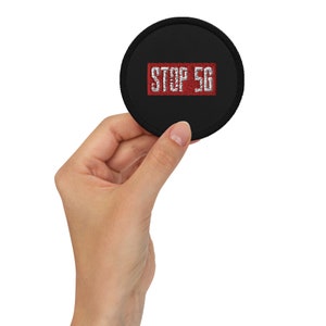 May include: A black round patch with white stitching. The patch has a red rectangle with the text "STOP 5G" in white.