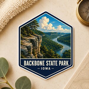 Könnte beinhalten: Ein sechseckiger Aufkleber mit einer Landschaftsillustration des Backbone State Park in Iowa. Das Bild zeigt felsige Klippen über einem gewundenen Fluss, umgeben von dichten grünen Wäldern unter einem blauen Himmel. Der Text lautet BACKBONE STATE PARK - IOWA.