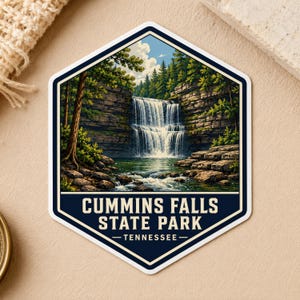 May include: A hexagonal sticker featuring a detailed illustration of a waterfall cascading over rocky cliffs into a pool, surrounded by pine trees. The text CUMMINS FALLS STATE PARK TENNESSEE is printed in white on a dark blue background at the bottom.