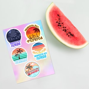 Puede incluir: Cuatro pegatinas redondas de colores con un diseño retro que presenta palmeras, una bicicleta y olas. Cada pegatina dice "Manasota Key Florida" en una fuente blanca.