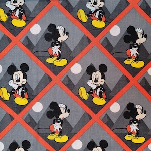 May include: A gray and red fabric with a repeating pattern of Mickey Mouse. Mickey Mouse is depicted in a variety of poses, including standing, sitting, and looking to the side. The background is a gray and red diamond pattern.