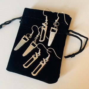 May include: A set of four silver earrings featuring miniature tool designs. The earrings are displayed in a black velvet pouch.