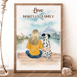 May include: A watercolor illustration of a woman and a dalmatian dog sitting on a wooden bench. The woman is wearing a yellow shirt and blue jeans. The dog is wearing a black collar. The background is a watercolor painting of a lake and mountains. The text "Love Makes Us Family" is written in black at the top of the image.