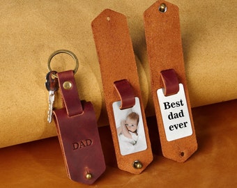 May include: Three leather keychains with different designs. One keychain has the word "DAD" embossed on it. Another keychain has a photo of a baby. The third keychain has the text "Best dad ever" on it.