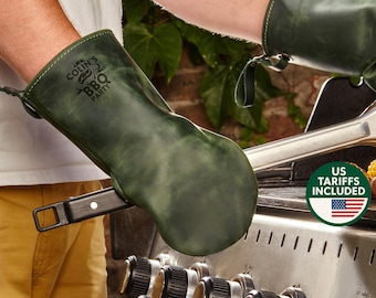 May include: Dark green leather BBQ mitts with the text "COLIN'S BBQ PARTY". The mitts are designed to protect hands from heat while grilling. The mitts are shown on a grill.