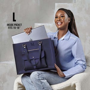 Può includere: Una grande borsa tote blu navy con tasca frontale, dettagli dorati e la lettera M monogrammata. La borsa presenta manici superiori e uno scomparto interno adatto a contenere un computer portatile da 38 a 41 cm.