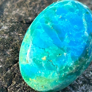 May include: A smooth, oval-shaped turquoise stone with a swirling pattern of blue and green hues.