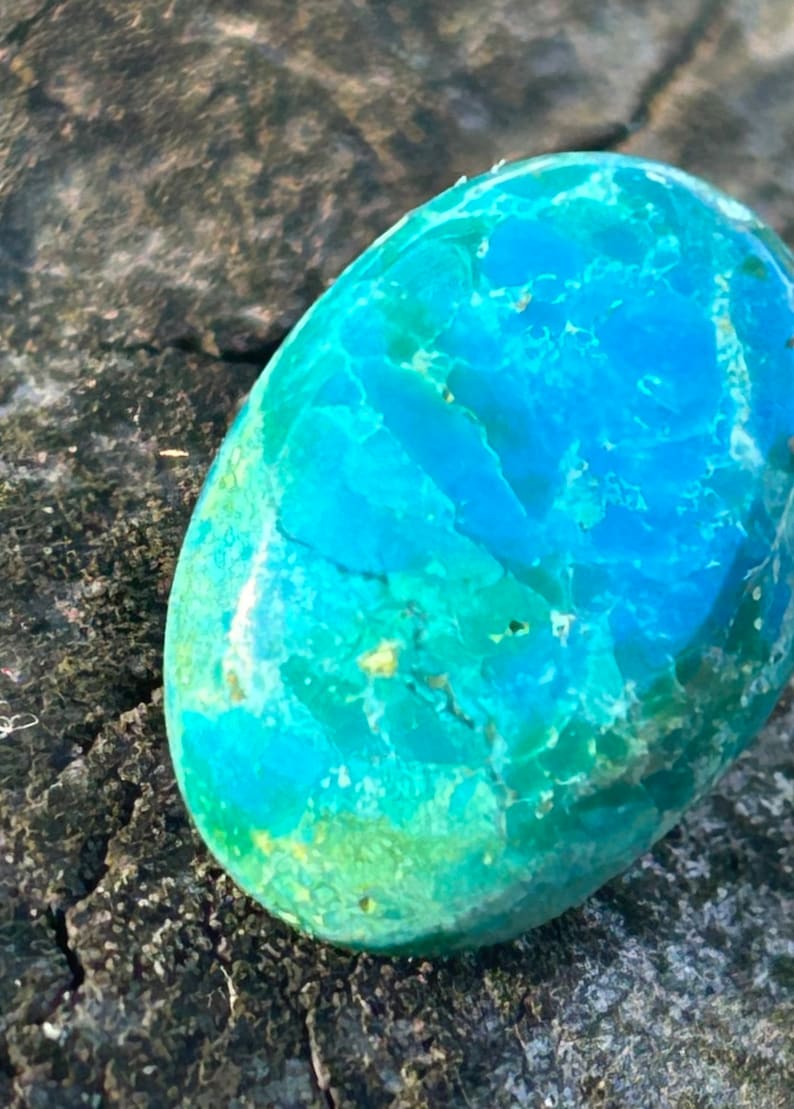 May include: A smooth, oval-shaped turquoise stone with a swirling pattern of blue and green hues.