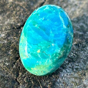 May include: A smooth, oval-shaped turquoise gemstone with a blue and green marbled pattern.