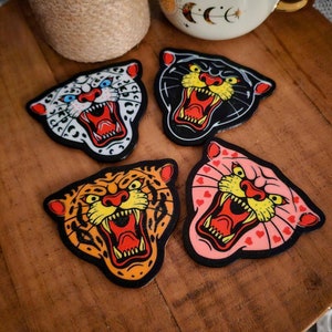 May include: Four colorful coasters featuring different animal faces with open mouths and sharp teeth. The coasters are made of a thick, durable material and are perfect for protecting your furniture from scratches and spills.