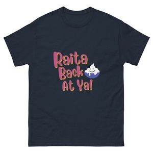 Può includere: Una t-shirt blu navy con il testo "Raita Back At Ya!" in lettere rosa e gialle. Un'immagine di un cartone animato di una ciotola di yogurt con un viso sorridente è accanto al testo.