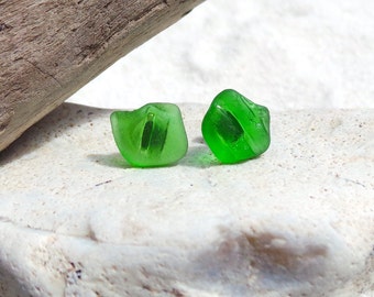 Puede incluir: Un par de pendientes de vidrio verde, cada uno con forma de pequeño cubo irregular. Los pendientes están sobre una superficie blanca.