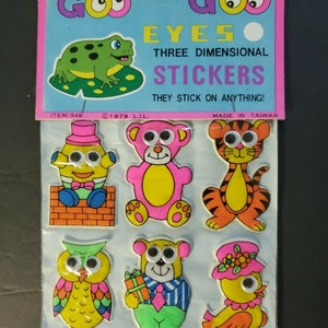 May include: Goo Goo Eyes Three Dimensional Stickers, a sheet of colorful stickers with googly eyes. The stickers feature a frog, a bear, a tiger, an owl, a bear with a gift, and a chick.