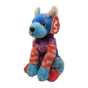May include: A colorful plush dog toy with blue, red, and pink accents. The dog has a blue head and paws, with red and white striped legs and a red collar. A red tag is attached to the ear.