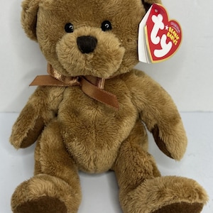 May include: A brown plush teddy bear with a brown ribbon tied around its neck. The bear has a tag that reads "Original Beanie Babies". The bear is sitting with its legs extended.