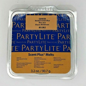 May include: A PartyLite Scent Plus wax melt in a clear plastic container. The wax melt is a light blue color and is labeled "Mediterranean Blue" with the product code "SX930". The container also includes the PartyLite logo and the weight of the wax melt, 3.2 oz / 90.7 g.